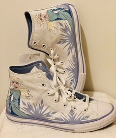 a pair of white shoes with frozen princess images on them