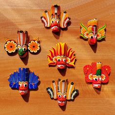 several colorful masks are arranged on a wooden surface