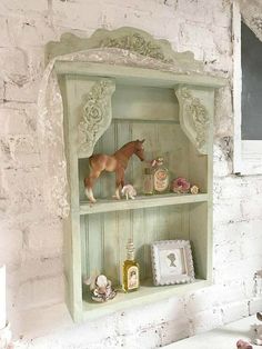 a white brick wall with an old fashioned shelf and horse figurines on it