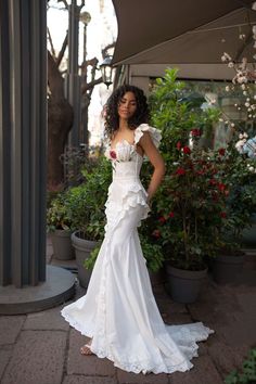 a woman in a white dress standing next to potted plants