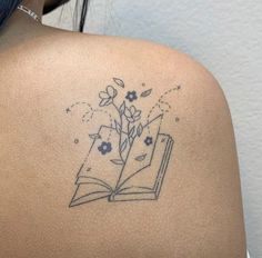 the back of a woman's shoulder with an open book and flowers on it