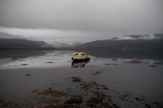 a small boat sitting on top of a wet beach