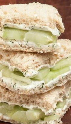 a stack of crackers with cucumbers and cream cheese on them sitting on a wooden table