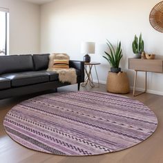 a living room with a black couch and purple rug