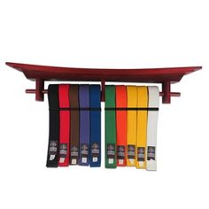 a red surfboard mounted on top of a wooden shelf filled with different colored belts