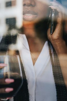 a woman talking on her cell phone while holding a wine glass in front of her