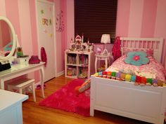 a child's bedroom with pink and white striped walls