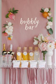 a table topped with lots of bottles of champagne next to vases filled with flowers