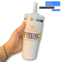 a hand holding a white tumbler cup with the word stanley on it's side