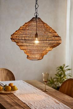 a wooden table topped with a plate of fruit and a light fixture hanging from the ceiling