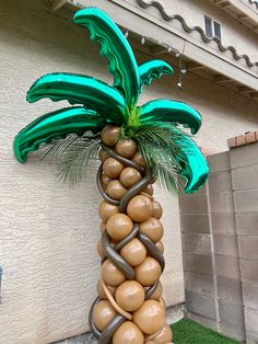 a palm tree made out of balloons on the side of a building in front of a house