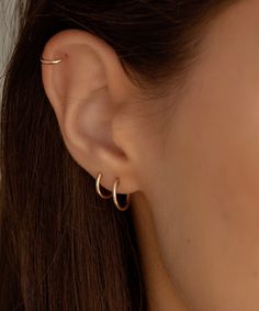 a close up view of a woman's ear with two small gold hoops