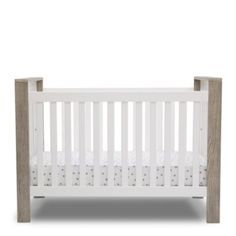 a small white crib with wood trimmings on the sides and bottom rails