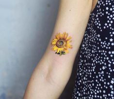 a woman's arm with a sunflower tattoo on the left side of her arm