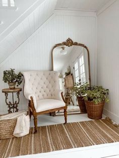 a room with a chair, mirror and potted plants on the floor in front of it