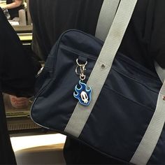 a blue bag with a keychain hanging from it's side in front of a person