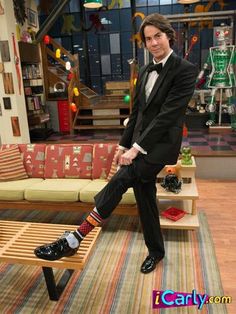 a man in a tuxedo is sitting on a bench and posing for the camera