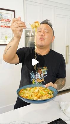 a man holding a plate of food in his hand and looking up at the camera