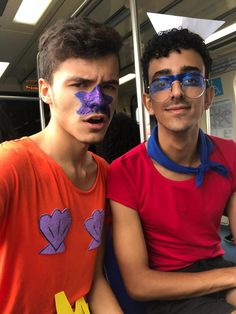 two young men sitting next to each other on a bus with their faces painted like hearts