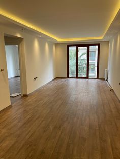 an empty room with hard wood flooring and large sliding glass doors to the outside