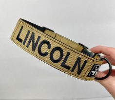 a hand holding a lanyard with the word lincoln on it and a black ring