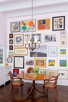 a dining room table surrounded by pictures on the wall