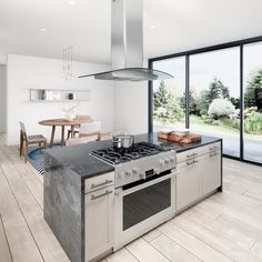 a kitchen with an oven, stove and dining table in front of large glass doors