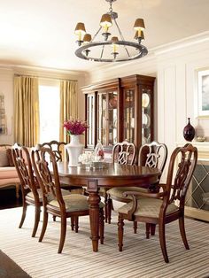 a dinning room table with chairs and a china cabinet in the back ground area