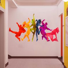 the colorful silhouettes of people are hanging on the wall in this hallway, and they appear to be made from paper