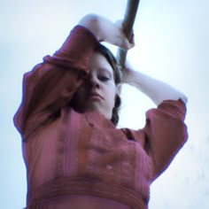 a woman in a pink dress holding a baseball bat up to her head with both hands