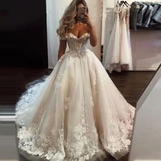 a woman taking a selfie in front of a mirror wearing a white wedding dress