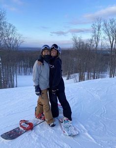 two people standing on top of a snow covered slope