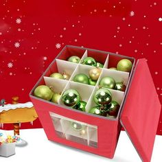 a red box filled with christmas ornaments next to a cake and other holiday decorations on a table