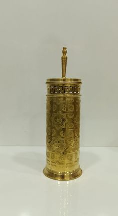 an ornately decorated gold canister sits on a white surface