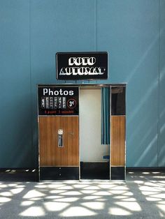 an old fashioned photo booth sitting in front of a blue wall