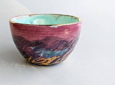 a purple and blue bowl sitting on top of a white table next to a wall