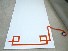 a white rug with an orange border on the floor next to a blue and red object