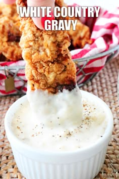 a person dipping some kind of food in a bowl with ranch dressing on the side