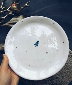 a person holding a white plate with a small blue star on the bottom and gold stars around it