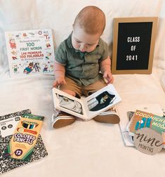 a baby is sitting on the bed reading a book and looking at it's contents