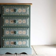 an old dresser with flowers painted on the front and drawers in blue, green and white