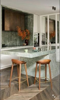 two stools are in front of an island counter with marble and wood on it