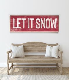 a wooden bench sitting in front of a wall with a sign that says let it snow