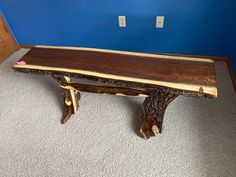 a wooden bench sitting on top of a carpeted floor next to a blue wall