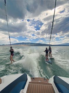 three people on surfboards in the water with one being pulled behind them by a boat