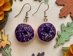 I've been enjoying the process of making seasonal donut earrings and thinking about what each season would look like if it was a donut, especially when considering their colors. One of the first Halloween colors I thought of was purple, and I knew I had to make purple donut earrings. I made these adorable purple iced Halloween donut earrings out of Sculpey polymer clay and using sculpting tools for the fine details of the donut cake texture and the frosting. I hand rolled each sprinkle and sprinkled them around the frosting layer. These will be perfect for Halloween parties, teacher gift, harvest festivals, or to wear during October. The drop length is 1 inch. Earring pins and hooks are Nickel Free. Purple Frosting, Harvest Festivals, Donut Earrings, Halloween Donuts, Sculpting Tools, Donuts Earrings, Flower Magnets, Teacher Halloween, Earring Pins