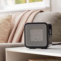 a black and white speaker sitting on top of a table next to a couch in a living room