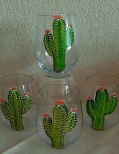 three wine glasses with painted cactus designs on the bottom one is clear and the other two are green