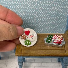 a hand is holding a small plate with christmas decorations on it and a miniature santa clause