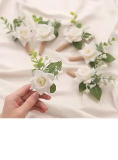 white flowers and greenery are arranged on a bed